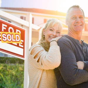 couple in front of home sold sign